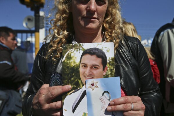 
              The wife of sailor Fernando Villarreal, a crew member of the missing submarine, shows his picture as she prays at the naval base in Mar de Plata, Argentina, Friday, Nov. 24, 2017. The Argentine navy says an explosion occurred near the time and place where the ARA San Juan submarine went missing on Nov. 15, leading some family members of the crew to give up hope of a rescue. (AP Photo/Esteban Felix)
            
