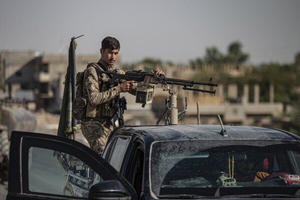 A U.S.-backed Syrian Democratic Forces (SDF) fighter stands on his armored vehicle, at al-Sabha town in the eastern countryside of Deir el-Zour, Syria, Monday, Sept. 4, 2023. Weeklong clashes between rival U.S.-backed militias in eastern Syria, where hundreds of American troops are deployed, point to dangerous seams in a coalition that has kept on a lid on the defeated Islamic State group for years. That could be an opportunity for the radical group to re-emerge. (AP Photo/Baderkhan Ahmad)