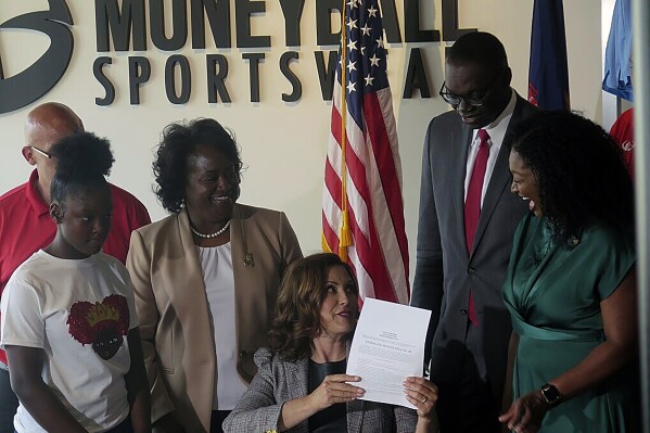 Michigan Gov. Gretchen Whitmer signs Crown Act legislation on Thursday, June 15, 2023 in Lansing, Mich. that will outlaw race-based hairstyle discrimination in workplaces and schools. State Sen. Sarah Anthony, far right, has pushed for the legislation since 2019. (AP Photo/Joey Cappelletti)