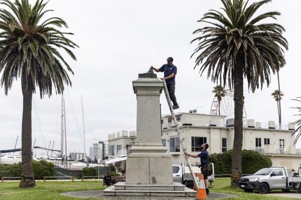 Workers remove the remnants of a Captain Cook statue in Melbourne, Australia, Thursday, Jan. 25, 2024, after vandals cut the statue off at the ankles. Two monuments symbolizing Australia's colonial past were damaged by protesters on Thursday ahead of an increasingly polarizing national holiday that marks the anniversary of British settlement. (Diego Fedele/AAP Image via AP)