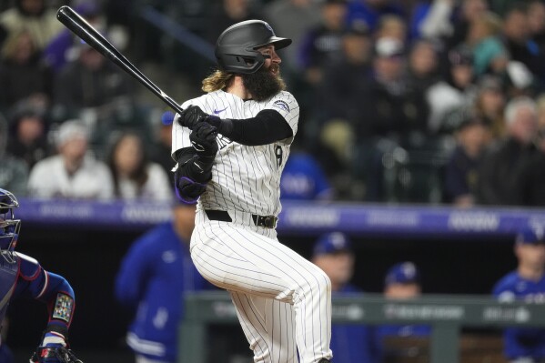 Colorado Rockies' Charlie Blackmon follows the flight of his double to drive in two runs off Texas Rangers relief Yerry Rodríguez in the eighth inning of a baseball game Friday, May 10, 2024, in Denver. (AP Photo/David Zalubowski)