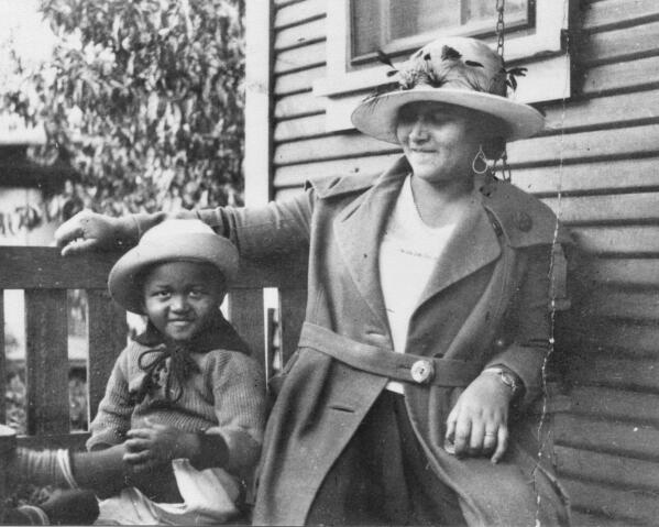 This photo provided by the Department of Special Collections, McFarlin Library, The University of Tulsa shows an African American woman and girl sitting on a porch swing, both dressed in coats and hats, by the side of a house. Provenance is unknown; however, it is believed that these photos were taken in Tulsa, Okla. prior to the Tulsa Race Massacre. (Department of Special Collections, McFarlin Library, The University of Tulsa via AP)