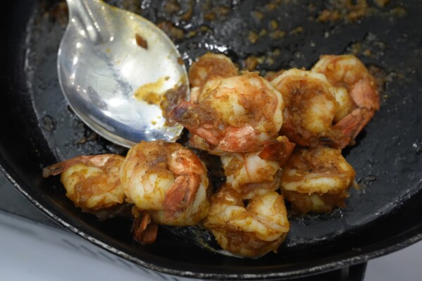 Seasoned sautéed shrimp rests in a pan at India's Marine Products Export Development Authority exhibit booth at the North American Seafood Expo, Monday, March 11, 2024, in Boston. (AP Photo/Steven Senne)