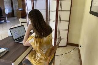 FILE - This file photo provided by Adrienne Robillard shows her daughter, name withheld by parent, doing school work at a computer at home in Kailua, Hawaii, Friday, Sept. 18, 2020. Hawaii's Department of Education is recommending that the state's public schools stop using a distance learning program that parents said had contained racist and sexist content. Schools across the nation have been using Acellus for distance learning and some have dropped the program after parent complaints. (Adrienne Robillard via AP, File)