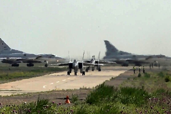 In this photo taken from video on Monday, June 10, 2024, and released by the Russian Defense Ministry Press Service, A pair of MiG-31 fighter jets of the Russian air force taxi out for a training mission with two Tu-22M3 bombers seen in the background during joint Russian-Belarusian drills intended to train the military to use tactical nuclear weapons. (Russian Defense Ministry Press Service via AP)