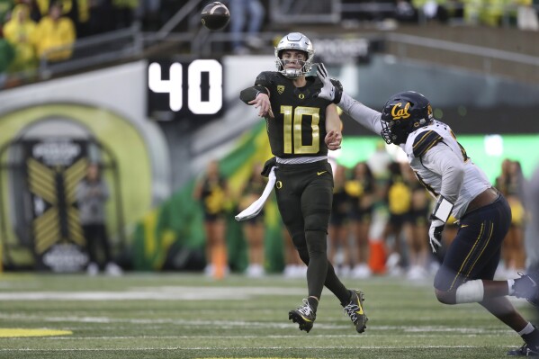 Oregon quarterback Bo Nix (10) throws a pass as California linebacker Xavier Carlton, right, defends during the first half of an NCAA football game, Saturday, Nov. 4, 2023, in Eugene, Ore. (AP Photo/Amanda Loman)