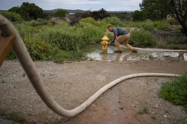 Garnett Querta fills his water truck from a fire hydrant on the Hualapai reservation Monday, Aug. 15, 2022, in Peach Springs, Ariz. The water pulled from the ground here will be piped dozens of miles across the rugged landscape to serve the roughly 600,000 tourists a year who visit the Grand Canyon on the Hualapai reservation in northwestern Arizona — an operation that's the tribe's main source of revenue. (AP Photo/John Locher)