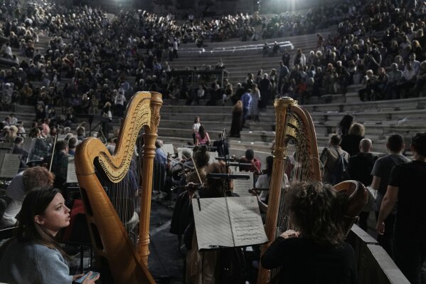 The two harpists of the Greek National Opera Ersilia Mikrou, left, and Anna Dermani watch the spectators taking their seats at the Odeon of Herodes Atticus ahead of Giacomo Puccini's "Turandot" dress rehearsal during the 70th Athens Epidaurus Festival in Athens, Greece, Friday, May 30, 2025. (AP Photo/Thanassis Stavrakis)