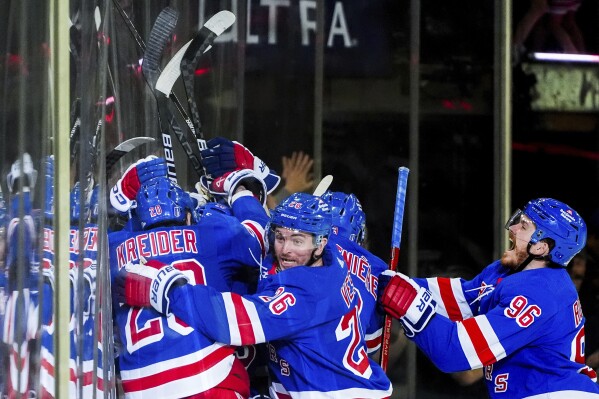 New York Rangers left wings Chris Kreider (20) and Jimmy Vesey (26), center Jack Roslovic (96) and other players react to center Vincent Trocheck's (16) game-winning goal in the second overtime in Game 2 of an NHL hockey Stanley Cup second-round playoff series against the Carolina Hurricanes, Tuesday, May 7, 2024, in New York. The Rangers won 4-3. (AP Photo/Julia Nikhinson)