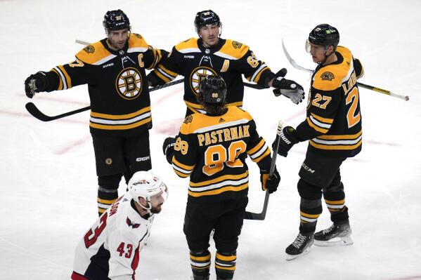 Boston Bruins left wing Brad Marchand, center rear, is congratulated after his goal against the Washington Capitals during the second period of an NHL hockey game Tuesday, April 11, 2023, in Boston. At bottom is Capitals right wing Tom Wilson. (AP Photo/Charles Krupa)