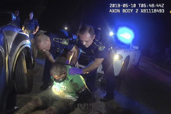 FILE - In this image from the body camera of Louisiana State Police Trooper Dakota DeMoss, his colleagues, Kory York, center left, and Chris Hollingsworth, center right, hold up Ronald Greene before paramedics arrived on May 10, 2019, outside of Monroe, La. An autopsy ordered by the FBI listed “prone restraint” among the other contributing factors in Greene’s violent death, including neck compression, physical struggle and cocaine use. (Louisiana State Police via AP, File)