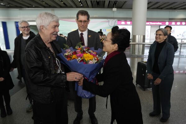 Philadelphia Orchestra's 73-year-old violinist Davyd Booth, left, is greeted by a representative of the Chinese People's Association for Friendship with Foreign Countries Cultural Exchange Department in Beijing Capital International Airport on Tuesday, Nov. 7, 2023. Musicians from the Philadelphia Orchestra arrived in Beijing on Tuesday, launching a tour commemorating its historic performance in China half a century ago in signs of improving bilateral ties ahead of a highly anticipated meeting between President Joe Biden and Xi Jinping. (AP Photo/Ng Han Guan)