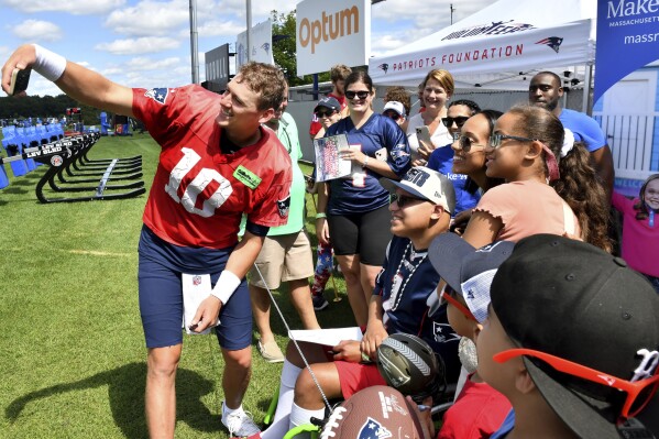 New England Patriots quarterback Mac Jones (10) takes a photo with fans at the end of an NFL football practice, Sunday, July 30, 2023, in Foxborough, Mass. (AP Photo/Mark Stockwell)