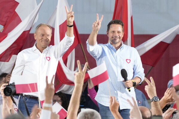 Poland's opposition leader and former prime minister, Donald Tusk, left, and his Civic Platform member, Warsaw Mayor Rafal Trzaskowski, right, flash victory signs during an election campaign rally in Otwock, Poland, on Monday, Sept. 25, 2023. Tusk is leading a march in Warsaw on Sunday aimed at mobilizing supporters in his against-the-odds battle to unseat the right-wing government in the Oct. 15 parliamentary election. (AP Photo/Czarek Sokolowski)