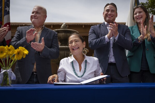 Interior Secretary Deb Haaland smiles after signing Public Land Order 7940, which protects more than 4,200 acres of Bureau of Land Management-managed public lands that is sacred to Tribes in the Placitas area, during a community event at El Zócalo Plaza in Bernalillo, N.M., Thursday, April 18, 2024. For the next 50 years, the lands will be closed to new mining claims, mineral sales, and oil and gas leases. (Chancey Bush/The Albuquerque Journal via AP)