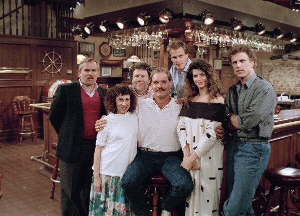 FILE -Boston Red Sox third baseman Wade Boggs, center, poses, March 2, 1988, with the cast of "Cheers" during rehearsal for an episode in which he appears. Cast members include, John Ratzenberger, Rhea Perlman, George Wendt, Woody Harrelson, Kirstie Alley and Ted Danson. (AP Photo/Ira Mark Gostin, File)