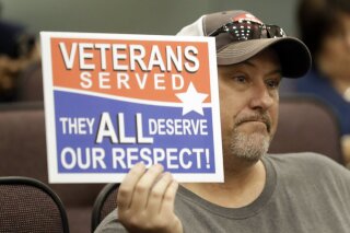 
              Steve Damron, 50, of Spring Hill, Fla., holds up a sign during a Hillsborough County Commission meeting about possible moving of a Confederate statue Wednesday, Aug. 16, 2017, in Tampa, Fla. Damron said the President Donald Trump handled the Charlottesville situation well, and he agreed with Trump that "both sides" were to blame. (AP Photo/Chris O'Meara)
            