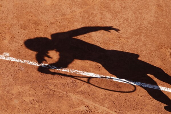 FILE - A tennis player casts a shadow on the clay court of the French Open tennis tournament at the Roland Garros stadium in Paris, Sunday, June 2, 2019. Tennis appears set to follow the path of golf and other sports by doing business with Saudi Arabia and its $650 billion sovereign wealth fund. (AP Photo/Christophe Ena, File)