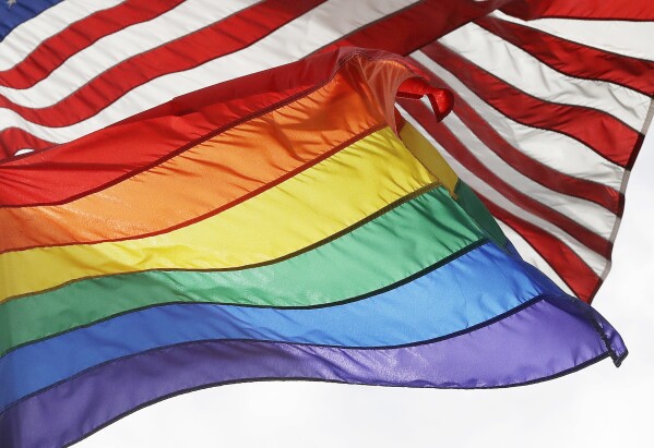 The LGBTQ+ pride flag flies beneath the American flag at the Stonewall National Monument, Oct. 11, 2017, in New York. (AP Photo/Mark Lennihan, File)