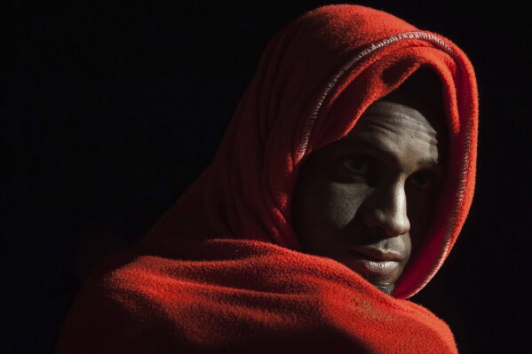 A man rescued by Spanish maritime authorities stand with a group of migrants on a rescue vessel as they arrive at Malaga port, Spain, Tuesday, Feb. 11, 2020. Spain on Monday rescued 119 migrants from the sea and was looking for 67 more believed to have gone missing on a boat while trying to reach European shores, the country's maritime authorities said on Monday. (AP Photo/Jesus Merida)
