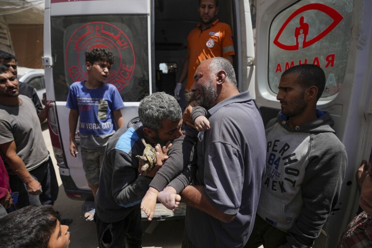 Palestinians hold the body of a dead baby rescued from the rubble of a building destroyed in an Israeli airstrike in Nuseirat, Gaza Strip, Tuesday, May 14, 2024. (AP Photo/Abdel Kareem Hana)