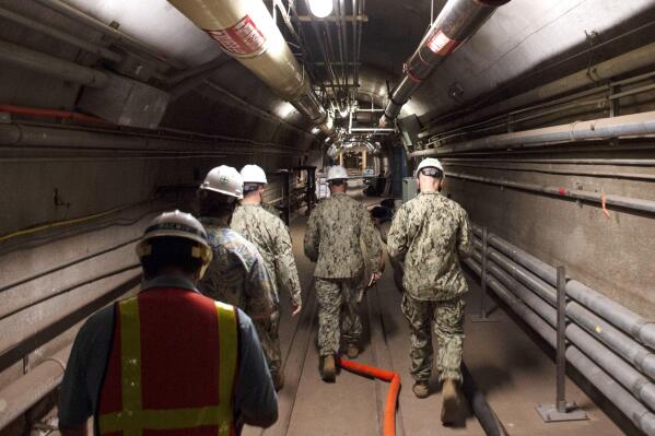In this Dec. 23, 2021, photo provided by the U.S. Navy, Rear Adm. John Korka, Commander, Naval Facilities Engineering Systems Command (NAVFAC), and Chief of Civil Engineers, leads Navy and civilian water quality recovery experts through the tunnels of the Red Hill Bulk Fuel Storage Facility, near Pearl Harbor, Hawaii. The Navy is scrambling to contain what one lawmaker has called a "crisis of astronomical proportions" after jet fuel leaked from an 80-year-old Hawaii tank farm, seeped into a drinking water well and polluted the water streaming out of faucets in Pearl Harbor military housing. (Mass Communication Specialist 1st Class Luke McCall/U.S. Navy via AP)