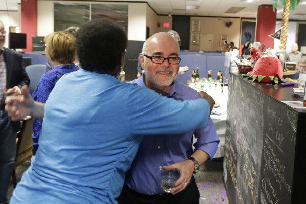FILE - Charlotte Observer editorial cartoonist Kevin Siers, right, gets a hug from a co-worker as the newsroom as they celebrate Siers winning the Pulitzer Prize for Editorial Cartooning at the newspaper in Charlotte, N.C., on Monday, April 14, 2014. Siers was among three Pulitzer Prize-winning editorial cartoonists who were laid off last week. (AP Photo/Chuck Burton, File)
