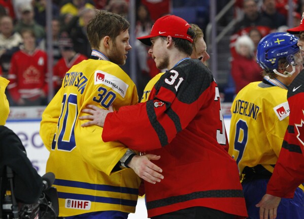 FILE - Canada goalie Carter Hart (31) and Sweden goalie Filip Gustavsson (30) greet one another following the gold medal game of the world junior hockey championships, Friday, Jan. 5, 2018, in Buffalo, N.Y. Canada won 3-1. The hockey governing body in the Canadian province of Newfoundland and Labrador has banned postgame handshakes in the minor leagues after a string of altercations. Instead of handshakes, officials will now direct teams off the ice after the game, according to The Canadian Press. (AP Photo/Jeffrey T. Barnes, File)