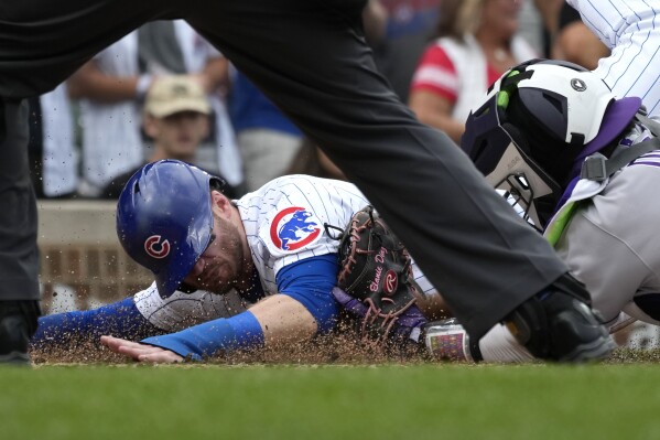 Chicago Cubs' Ian Happ, left, is tagged out by Colorado Rockies catcher Elias Diaz during the first inning of a baseball game in Chicago, Friday, Sept. 22, 2023. (AP Photo/Nam Y. Huh)