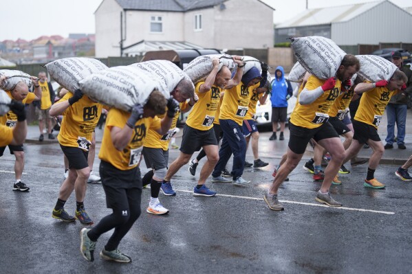 Contestants take off from the start line carrying 50kg sacks of coal along a 1.1km course at the World Coal Carrying Championships in Ossett, West Yorkshire, England, Monday, April 21, 2025. (AP Photo/Jon Super)