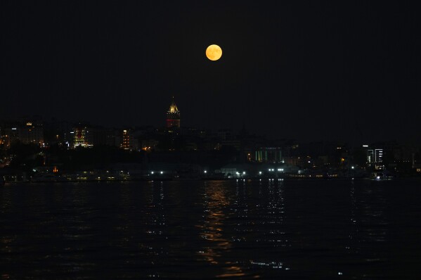 The full moon rises behind the Galata tower in Istanbul, Turkey, Wednesday, Aug. 30, 2023. (AP Photo/Khalil Hamra)