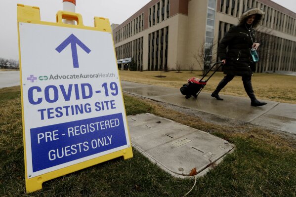 FILE - In this Wednesday, March 18, 2020 file photo, a pedestrian walks past a COVID-19 testing sign at Advocate Lutheran General Hospital in Park Ridge, Ill. Some bored with the limitations of the term "COVID-19" and the even clunkier name of the virus that causes it — severe acute respiratory syndrome coronavirus 2 — have come up with their own shorthand. On Thursday, Eric Acton, a linguist at Eastern Michigan University, said, “One of my students just referred to the virus as “The Ronies,” after a research group meeting conducted virtually. (AP Photo/Nam Y. Huh)