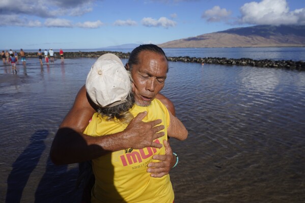 CORRECTS LAST NAME TO RUBIO, NOT RUBOI - Vicente Rubio receives a hug after performing a blessing to greeting the day Tuesday, Aug. 15, 2023, in Kihei, Hawaii. (AP Photo/Rick Bowmer)