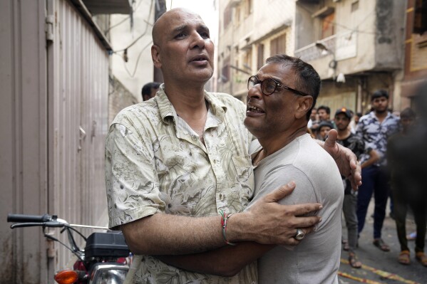 People react on the death of their relatives at the site of a fire incident, in Lahore, Pakistan, Wednesday, July 12, 2023. A fire swept through a house in Pakistan's eastern city of Lahore before dawn Wednesday, killing children and adults mostly of the same family, police and rescue officials said. (AP Photo/K.M. Chaudary)