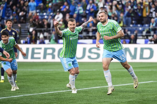 Seattle Sounders forward Jordan Morris, right, reacts with midfielder Albert Rusnák, center, after scoring against the Vancouver Whitecaps during the first half of an MLS soccer match Saturday, May 18, 2024, in Seattle. (AP Photo/Lindsey Wasson)