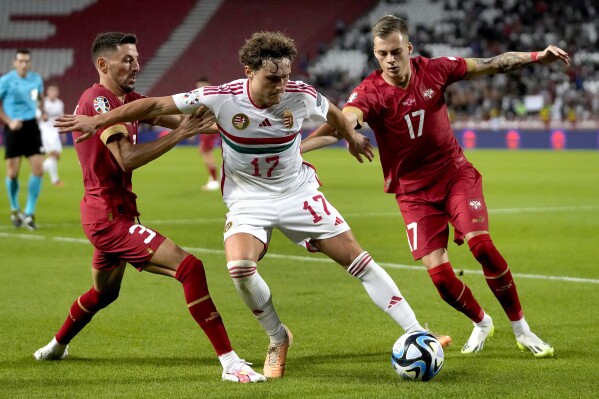 Serbia's Filip Mladenovic, left, and Serbia's Ivan Ilic, right challenge for the ball with Hungary's Callum Styles, center, during the Euro 2024 group G qualifying soccer match between Serbia and Hungary in Belgrade, Serbia, Thursday, Sept. 7, 2023. (AP Photo/Darko Vojinovic)
