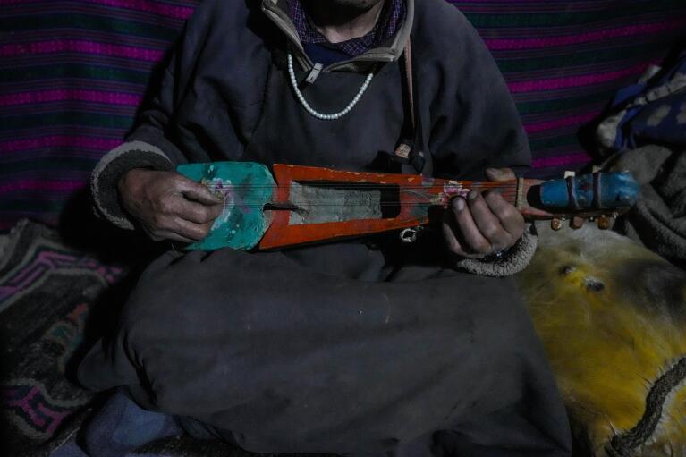 Nomad Tsering Choldan plays a traditional music instrument inside his mud house in remote Kharnak village in the cold desert region of Ladakh, India, Saturday, Sept. 17, 2022. As this part of Asia is particularly vulnerable to climate change, shifting weather patterns are altering people’s lives through floods, landslides and droughts in Ladakh, an inhospitable yet pristine landscape of high mountain passes and vast river valleys that in the past was an important part of the famed Silk Road trade route. (AP Photo/Mukhtar Khan)