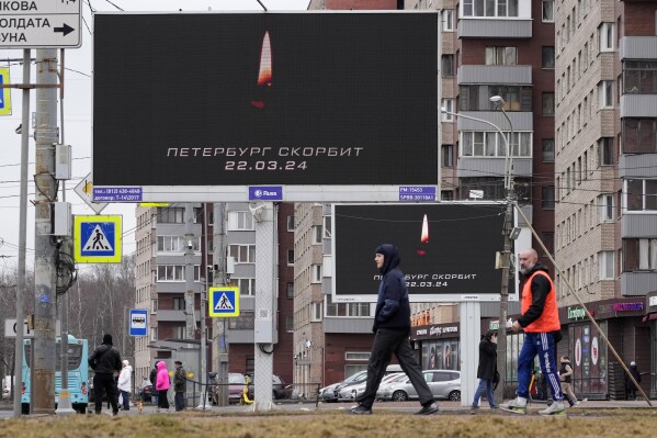 People walk past messages displayed on billboards that read: "St. Petersburg Mourns 03.22.2024", in St. Petersburg, Russia, Sunday, March 24, 2024. Russia observed a national day of mourning on Sunday, two days after an attack on a suburban Moscow concert hall that killed over 130 people. (AP Photo/Dmitri Lovetsky)