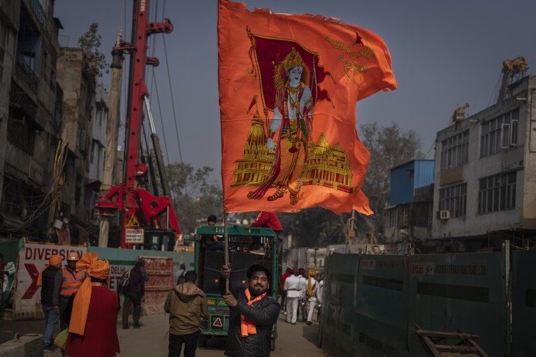 A Hindu man waves a huge flag featuring Hindu god Ram to celebrate the upcoming opening of a grand temple for the Lord Ram in northern Ayodhya city, during a procession in New Delhi, India, Tuesday, Jan. 16, 2024. (AP Photo/Altaf Qadri)