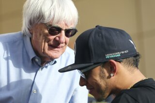 FILE - In this Thursday, April 16, 2015 file photo, Bernie Ecclestone, President and CEO of Formula One Management, left, talks to Mercedes driver Lewis Hamilton of Britain ahead the Bahrain Formula One Grand Prix at the Formula One Bahrain International Circuit in Sakhir, Bahrain. Formula One champion Lewis Hamilton has criticized “ignorant and uneducated” comments by former F1 boss Bernie Ecclestone. Hamilton, a six-time world champion and the only Black driver in F1, was shocked by Ecclestone's claim during an interview with broadcaster CNN on Friday, June 26, 202 that “in lots of cases, Black people are more racist” than white people. (AP Photo/Kamran Jebreili, File)
