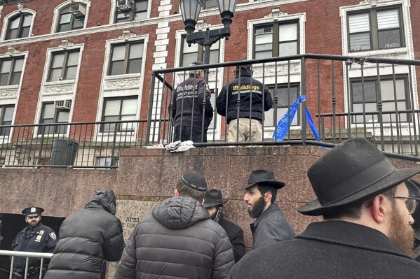 FILE - City inspectors and police officers outside the Brooklyn borough, N.Y., headquarters of the Chabad movement, Tuesday, Jan. 9, 2024. On Friday, Jan. 12, APreported on stories circulating online incorrectly claiming a secret underground tunnel found connected to the Chabad Lubavitch APHeadquarters was used for child sex trafficking or other illicit activities.(APPhoto/Jake Offenhartz)