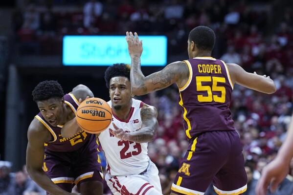 Wisconsin's Chucky Hepburn (23) passes the ball away from Minnesota's Pharrel Payne (21) and Ta'Lon Cooper (55) during the second half of an NCAA college basketball game Tuesday, Jan. 3, 2023, in Madison, Wis. (AP Photo/Andy Manis)