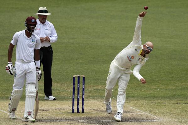 Australia's Nathan Lyon, right, bowls as West Indies' Roston Chase, left, watches on the 5th day of their cricket test in Perth, Australia, Sunday, Dec. 4, 2022. (AP Photo/Gary Day)