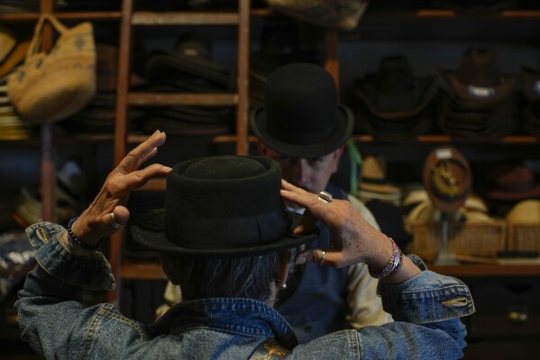 A customer tries on a hat at the “Donde Golpea el Monito” hat shop and museum that preserves a hat-making tradition dating back to 1915, in Santiago, Chile, Saturday, April 5, 2025. (AP Photo/Esteban Felix)