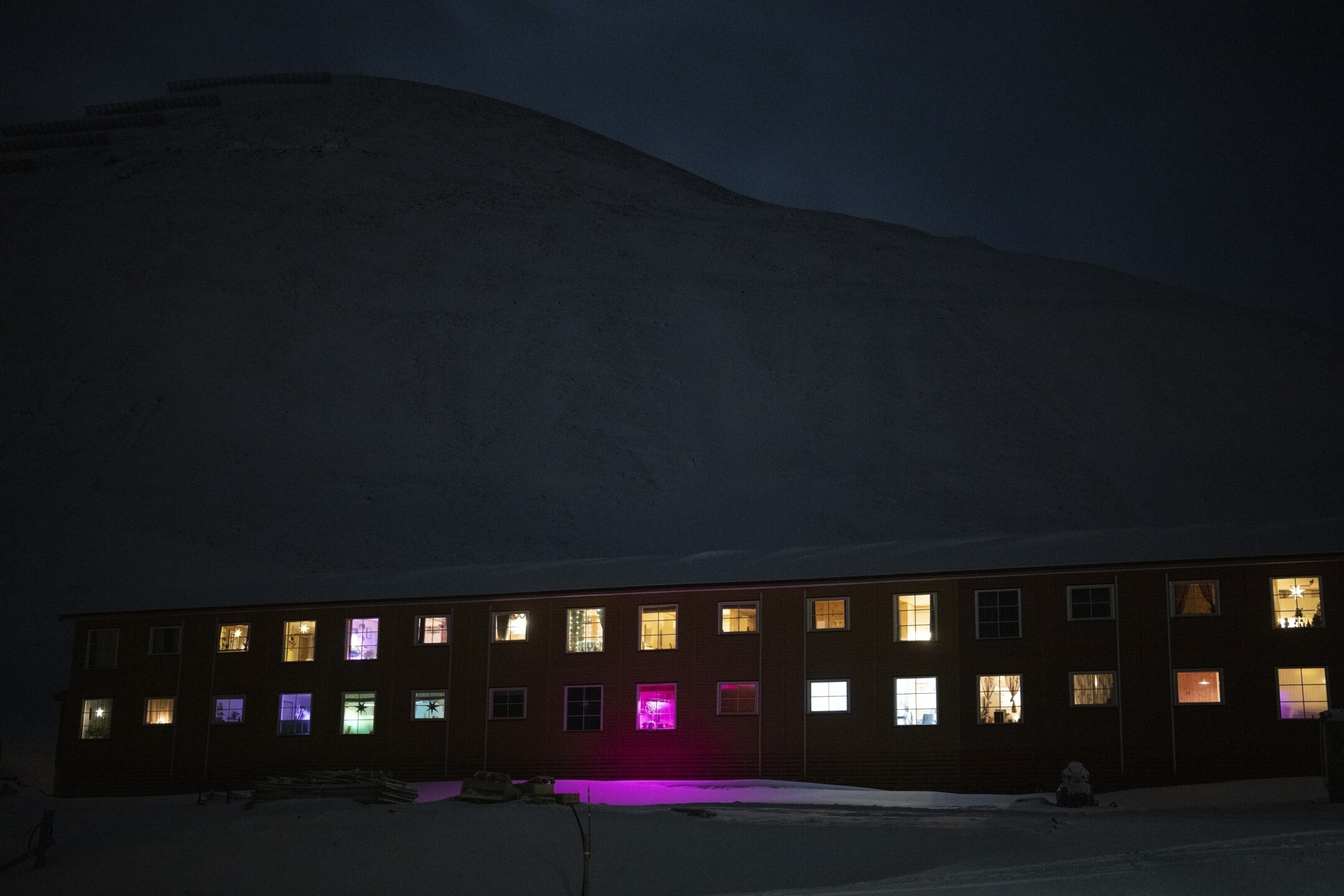 Windows light up the polar night on Jan. 6, 2023, in Longyearbyen, Norway, so close to the North Pole the sun is at least six degrees below the horizon from mid-November through the end of January. (AP Photo/Daniel Cole)