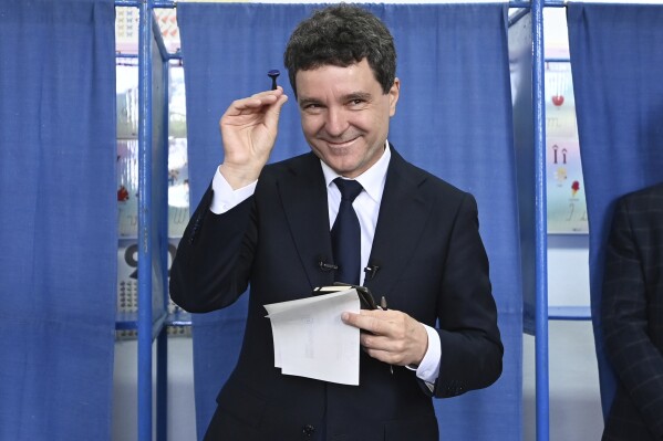 Presidential candidate Nicusor Dan smiles while holding a stamp before casting his ballot in the second round of the country's presidential election redo in Fagaras, Romania, Sunday, May 18, 2025. (AP Photo/Eduard Vinatoru)