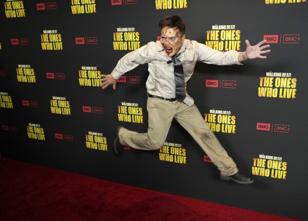 Actor Kurt Tocci leaps for photographers at the premiere of the AMC series "The Walking Dead: The Ones Who Live," Wednesday, Feb. 7, 2024, in Los Angeles. (AP Photo/Chris Pizzello)