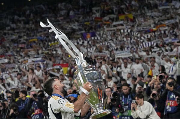 Real Madrid's Dani Carvajal shows the trophy to the supporters after winning the Champions League final soccer match between Borussia Dortmund and Real Madrid at Wembley stadium in London, Sunday, June 2, 2024. Real Madrid won 2-0. (AP Photo/Frank Augstein)