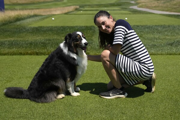 Lara Arias, a rare female golf course superintendent, poses for a photo with her Australian Shepard "Ryder" during an interview with the Associated Press, at the Marco Simone Club in Guidonia Montecelio, Italy, Tuesday, July 11, 2023. When Lara Arias started her job as course superintendent at the Marco Simone golf club outside Rome that will host the Ryder Cup from Sept. 29 to Oct.1 there was hardly any grass to manicure, no bunkers to rake and nary a green to shape, the entire course was practically one big pile of dirt amid a complete restyling. (AP Photo/Alessandra Tarantino)