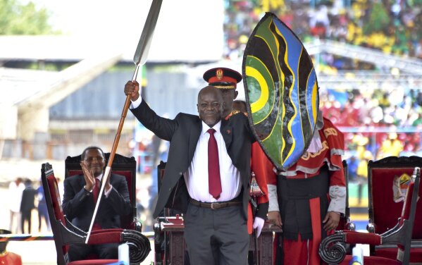 FILE - In this Nov. 5, 2015, file photo, Tanzania's President John Magufuli holds up a ceremonial spear and shield to signify the beginning of his presidency, shortly after swearing an oath during his inauguration ceremony at Uhuru Stadium in Dar es Salaam, Tanzania. As of late May 2020, the country’s number of confirmed coronavirus cases hasn’t changed for three weeks, and the international community is openly worrying that Tanzania’s government is hiding the true scale of the pandemic. Magufuli has led a crackdown on anyone who dares raise concerns about the virus’s spread or the government’s response. (AP Photo/Khalfan Said, File)